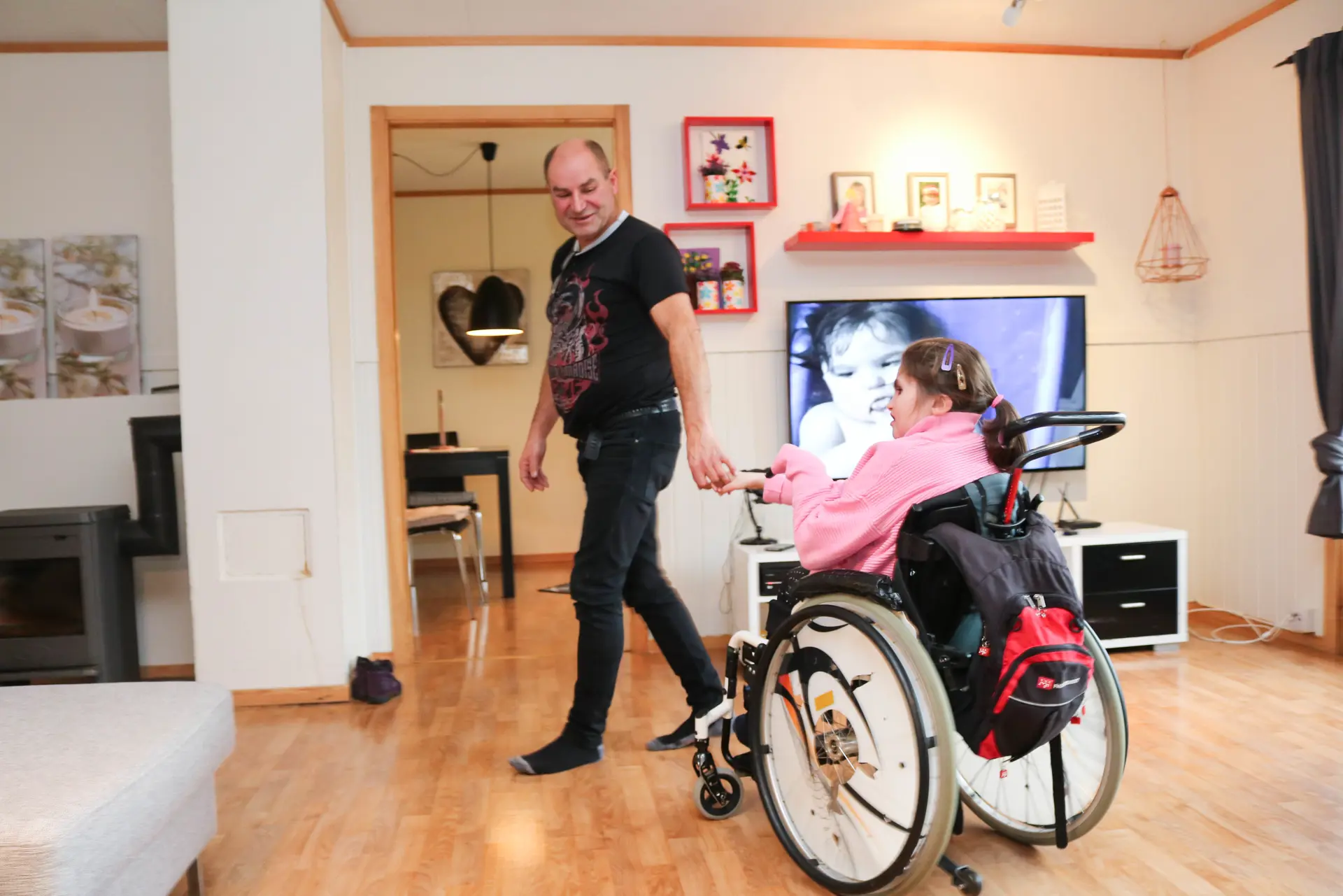 En mann som drar en kvinne i rullestol i et rom