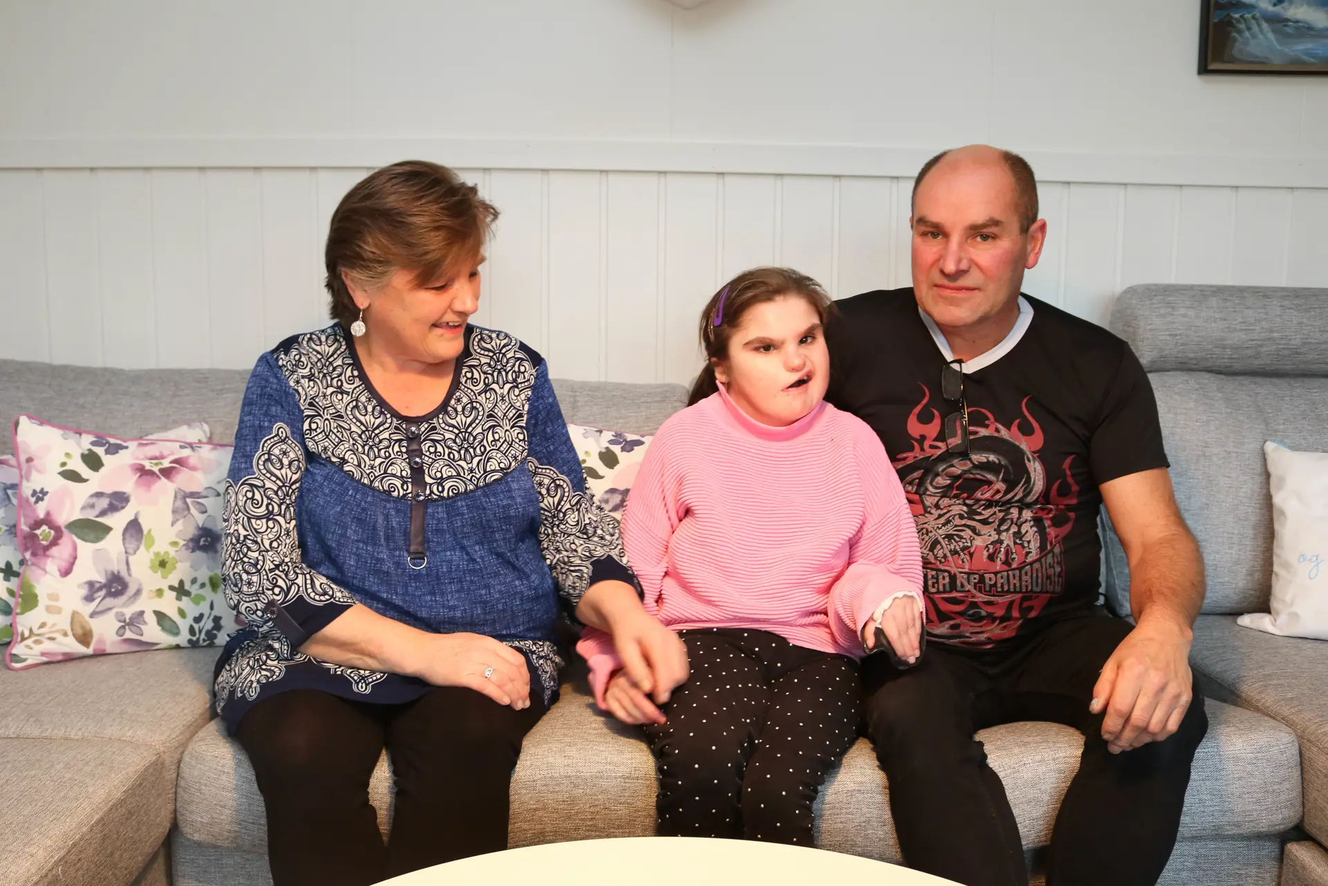 Voksen mann og kvinne og en ung kvinne sitter på en sofa