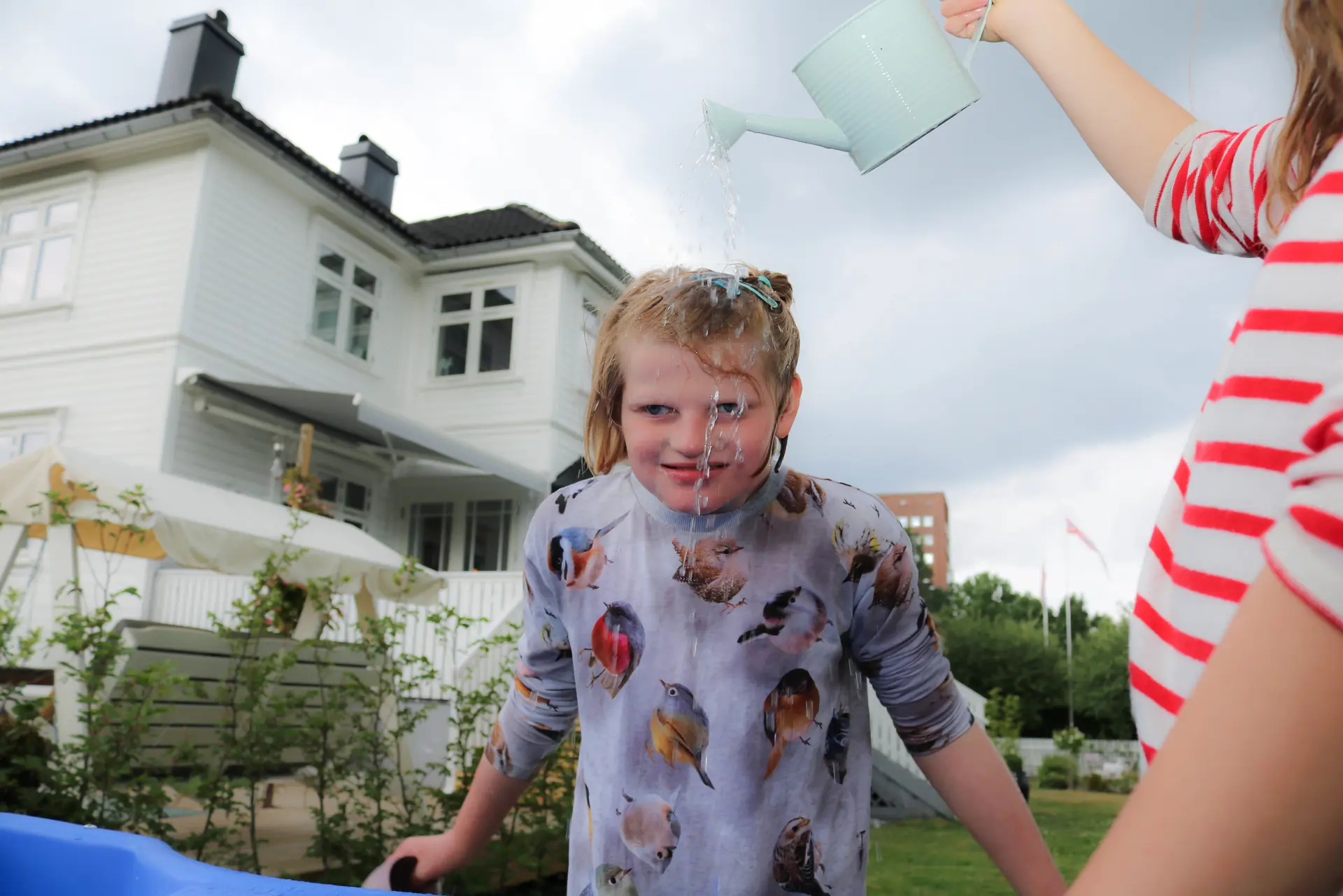 Jente står foran hvit trevilla, hun lener seg fremoverJente står foran hvit trevilla, hun lener seg fremover