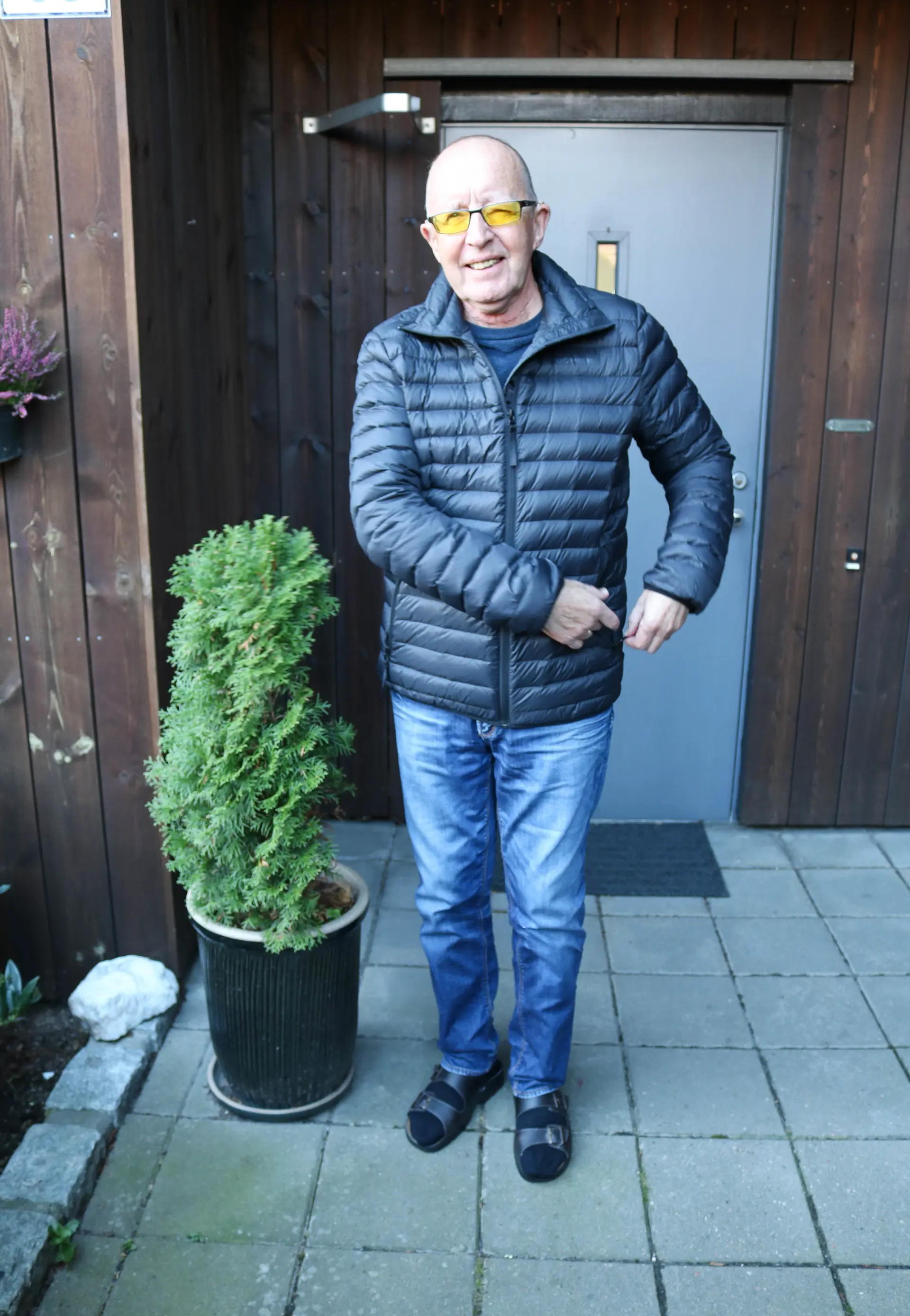 En mann iført blå boblejakke som står foran en dør