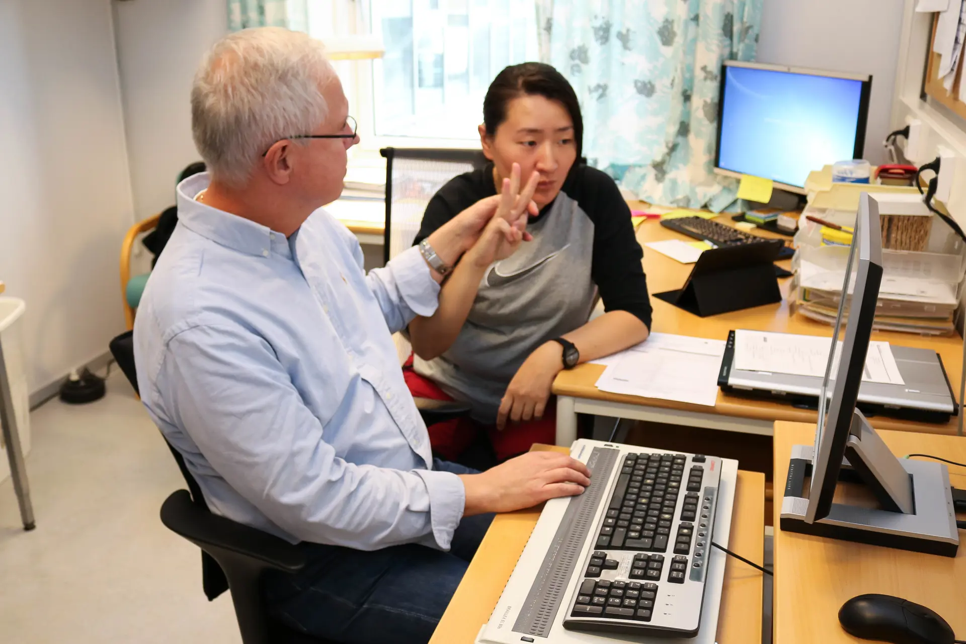 En mann og en kvinne som sitter ved et skrivebord med datamaskiner
