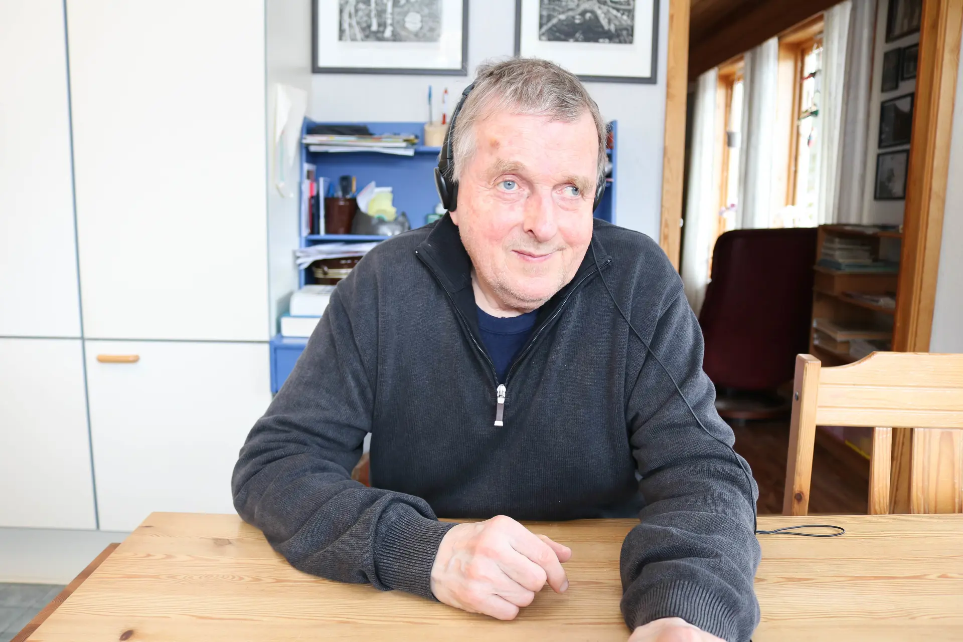 En mann i grå genser som sitter ved et bord