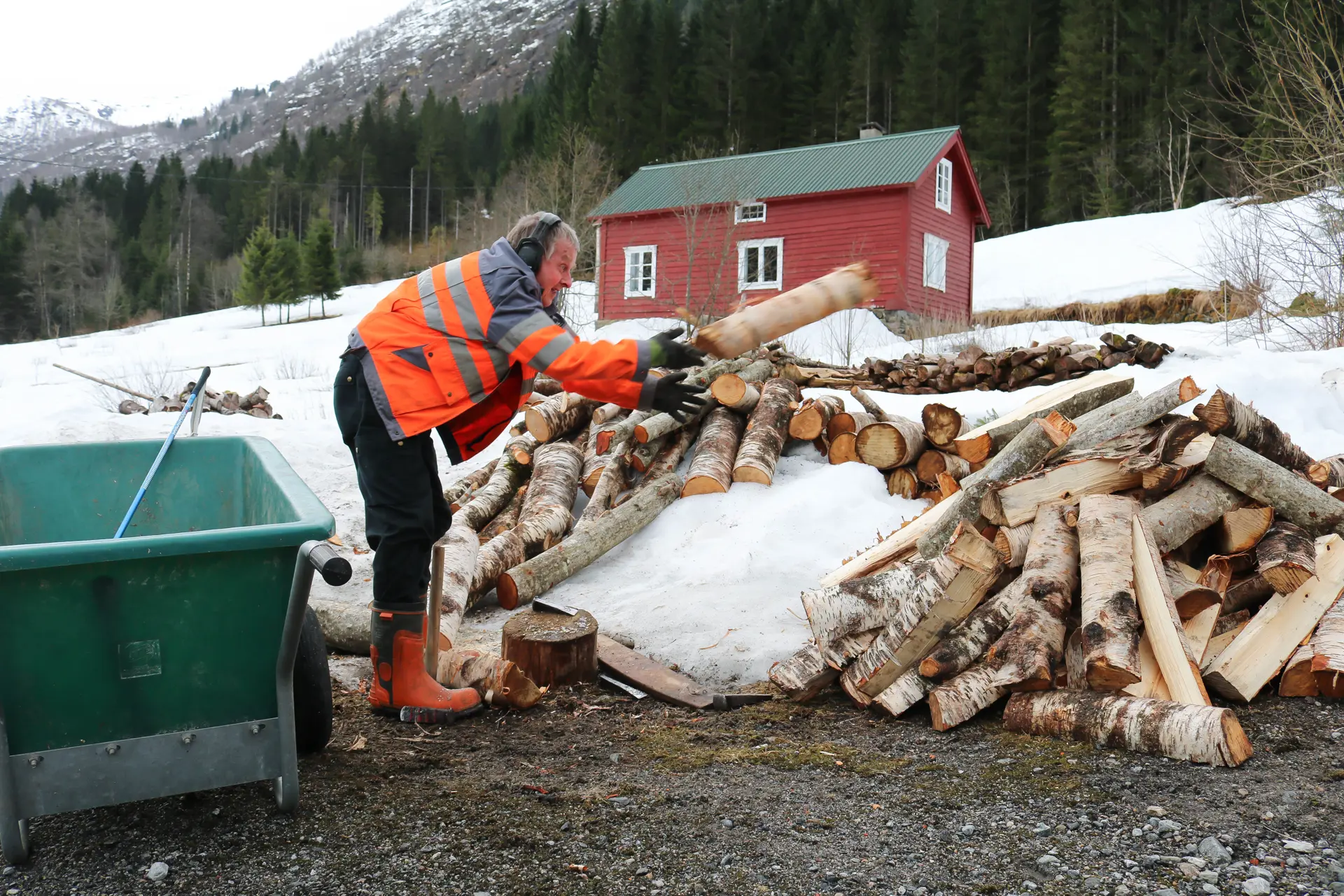 Mann som hiver trestokker i  en haug