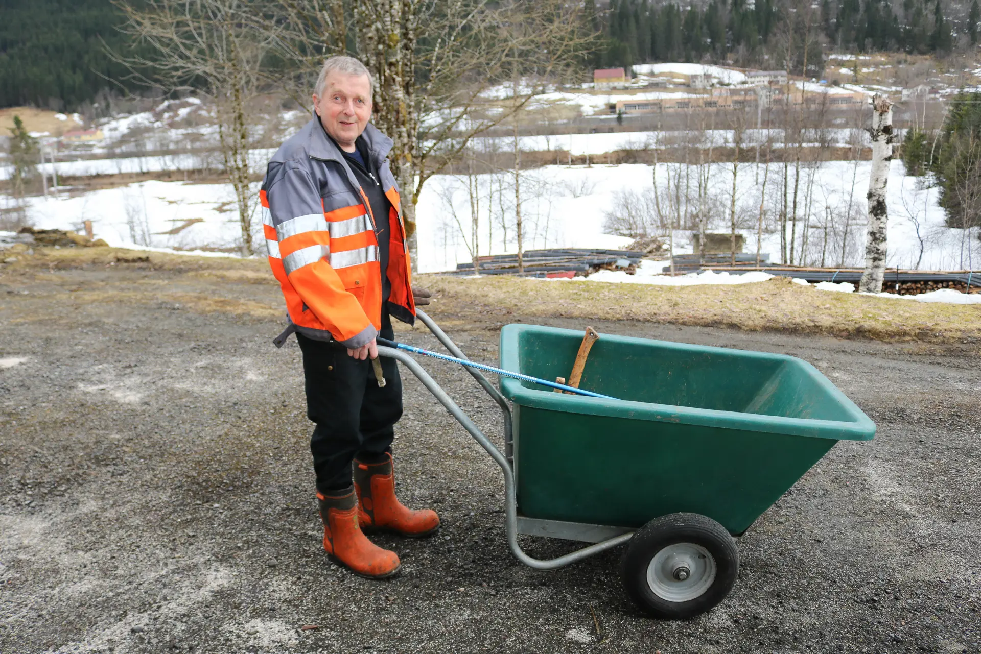 Mann som triller grønn trillebår