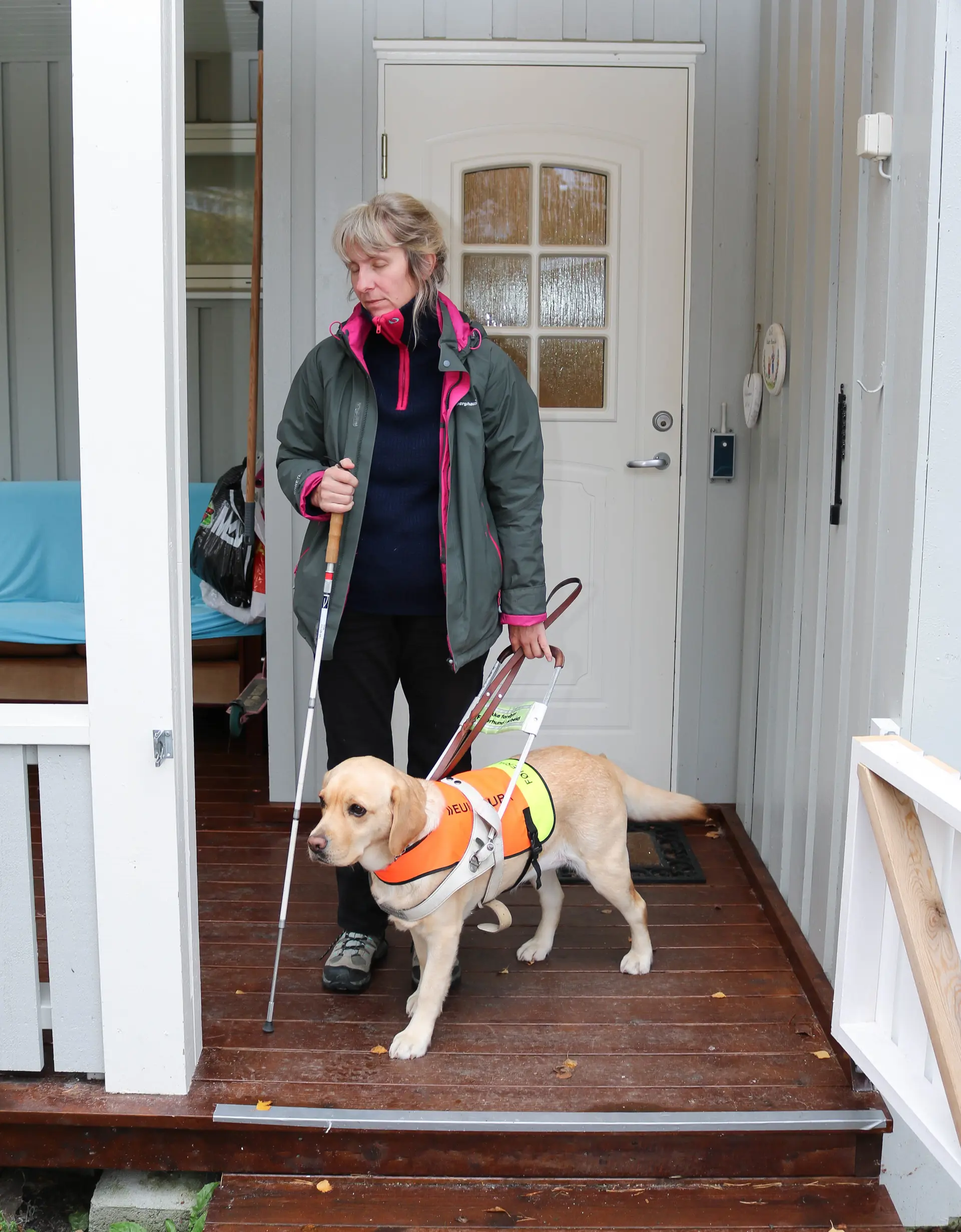 Blindestokkalbue Øie er en av dem som stiller seg uforstående til at andre døvblinde ikke vil bruke blindestokk. Hun begynte tidlig å ha med seg stokken i nødstilfelle.  - Jeg pleier å si at jeg ikke har tennisalbue, men blindestokkalbue. På 20 år har jeg bare mistet stokken én gang, fordi noen var uheldige å sparke den bort på en buss, smiler hun og forteller om flere komiske småuhell med stokken.  - Jeg tok buss sammen med en venninne, og skulle til å brette sammen stokken min, da den plutselig føyk rett ut og traff hatten til en mann som satt foran oss. Oi-oi, det var ikke helt bra, han ble jo nesten overfalt stakkars.  En annen gang fikk hun ikke med seg tolk på tjenestereise i Nord-Norge. Hun tenkte at det ikke var så farlig, siden hun var godt kjent i området hun skulle på jobb. Hun reiste alene med taxi, fly og buss. På en flyplass ble hun stående i en butikk og se på potensielle julegaver.  - Jeg fant et veldig fint veggteppe, som jeg ville kjøpe. Men så begynte teppet å bevege på seg. Jeg skvatt til og det viste seg at «teppet» var jakka til en høy mann. «Du har en veldig fin jakke...», sa jeg til ham og var veldig  glad for at jeg hadde blindestokken med meg, forteller hun og ler høyt.  Det siste året har blindestokkalbuen slått til igjen for henne. Hun klarer derfor ikke å bruke blindestokk aktivt. Hele høyre armen hennes ble betent sommeren 2017, og hun må fremdeles være forsiktig med å løfte og bære ting.  Foran ytterdør. Kvinne er på vei ut med sin førerhund, hun holder en blindestokk i høyrearm. Øynene hennes er lukket.