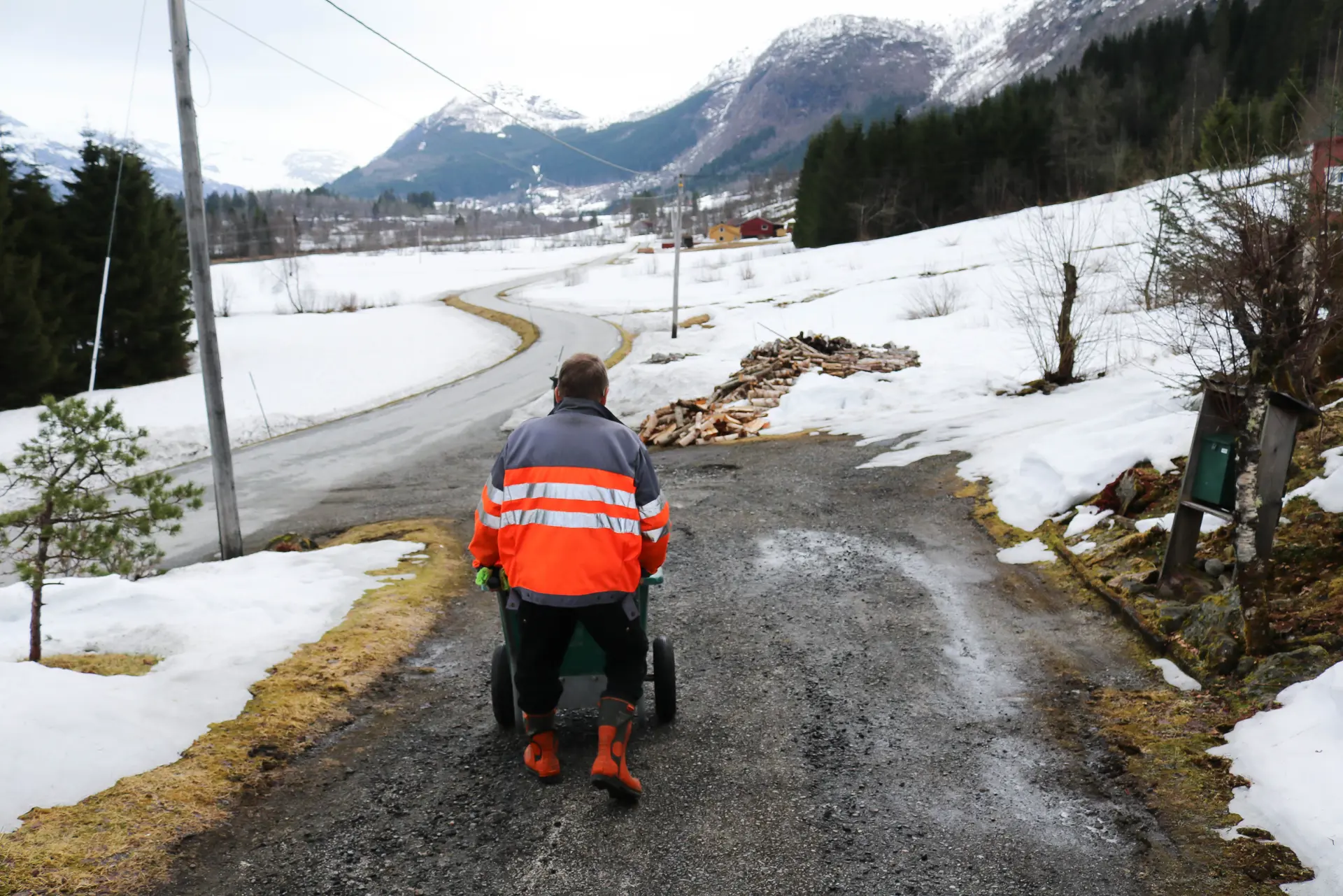 En mann som triller en trillebår på en landevei