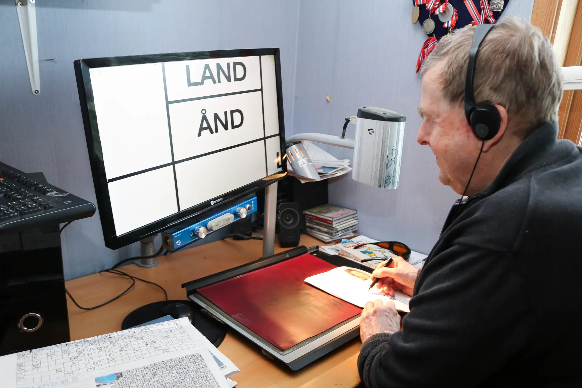 En mann med hodetelefoner og sitter ved et skrivebord med en datamaskin