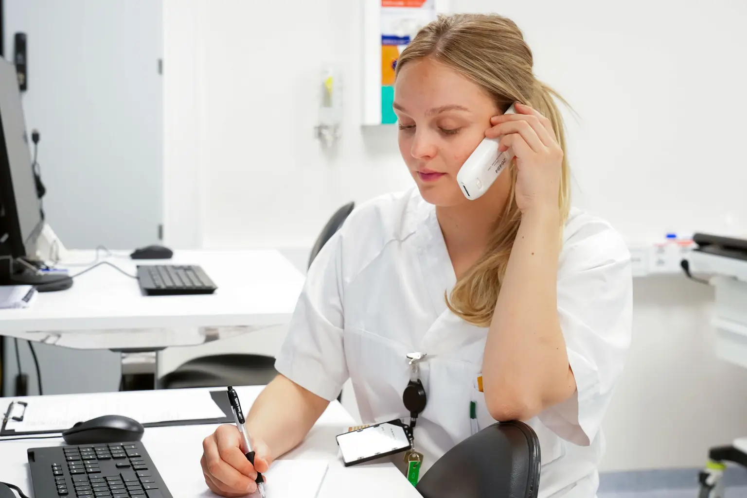 En person som sitter ved et skrivebord med headset på