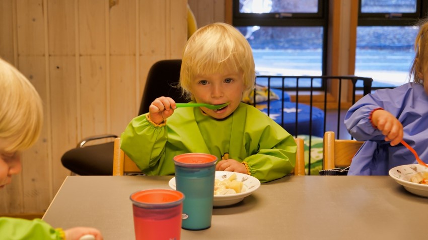 Et barn som spiser mat ved et bord