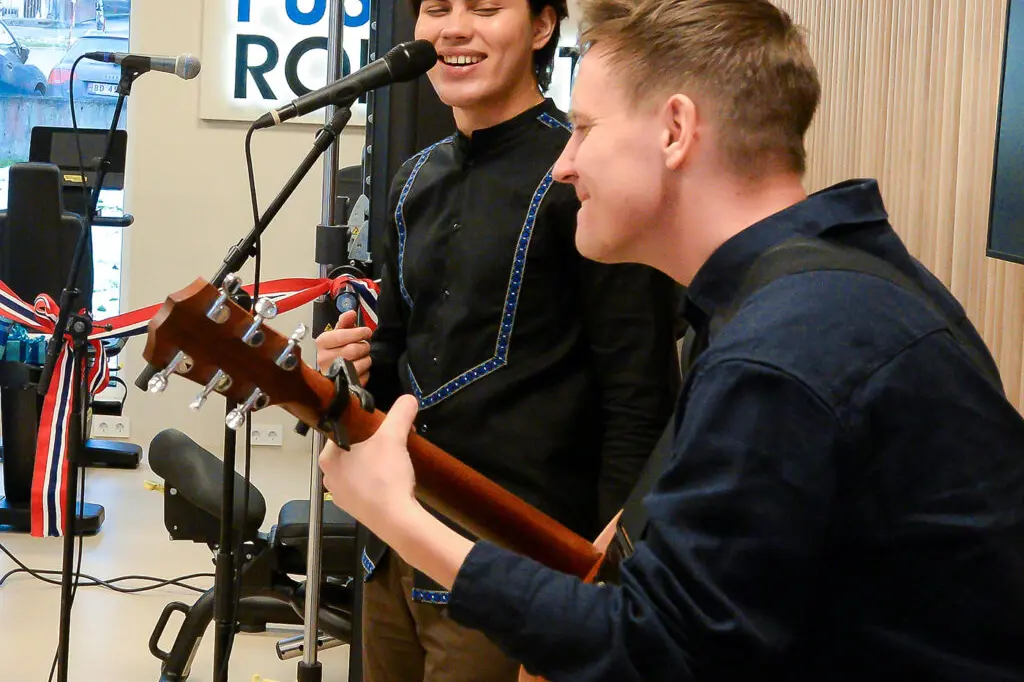 En mann som spiller gitar ved siden av en mann som spiller et musikkinstrument