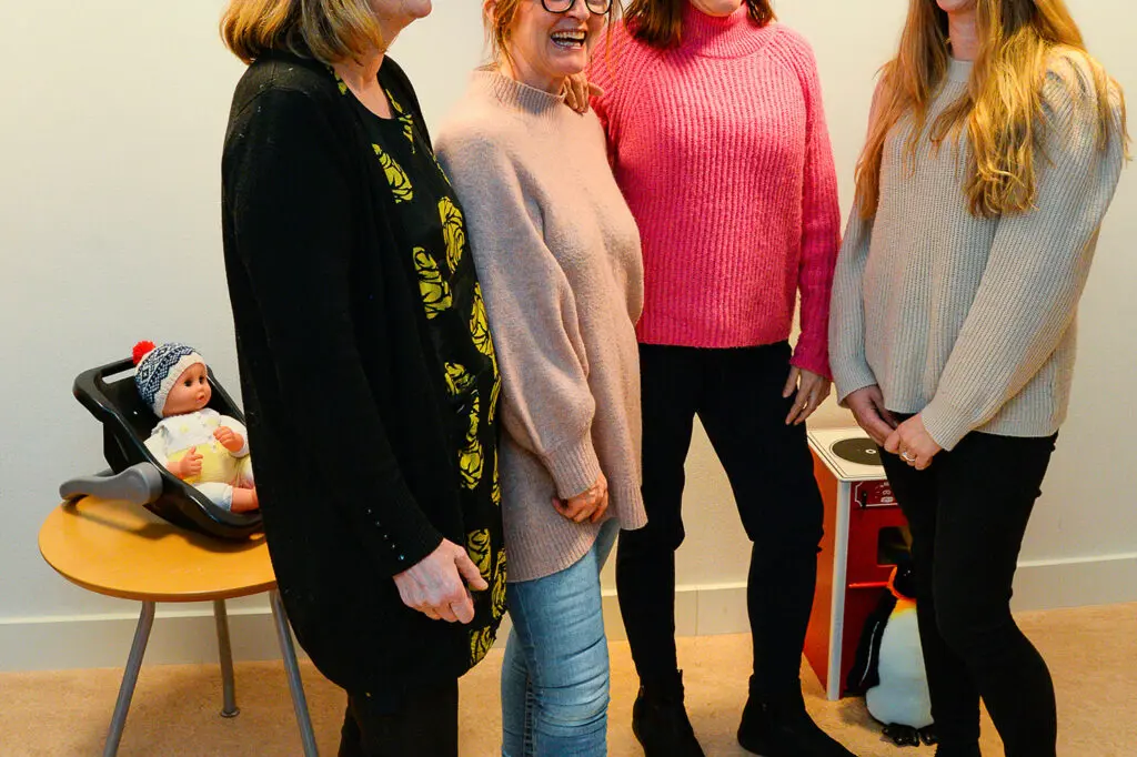 Fire personer som smiler og ler, leker på gulv og bak dem