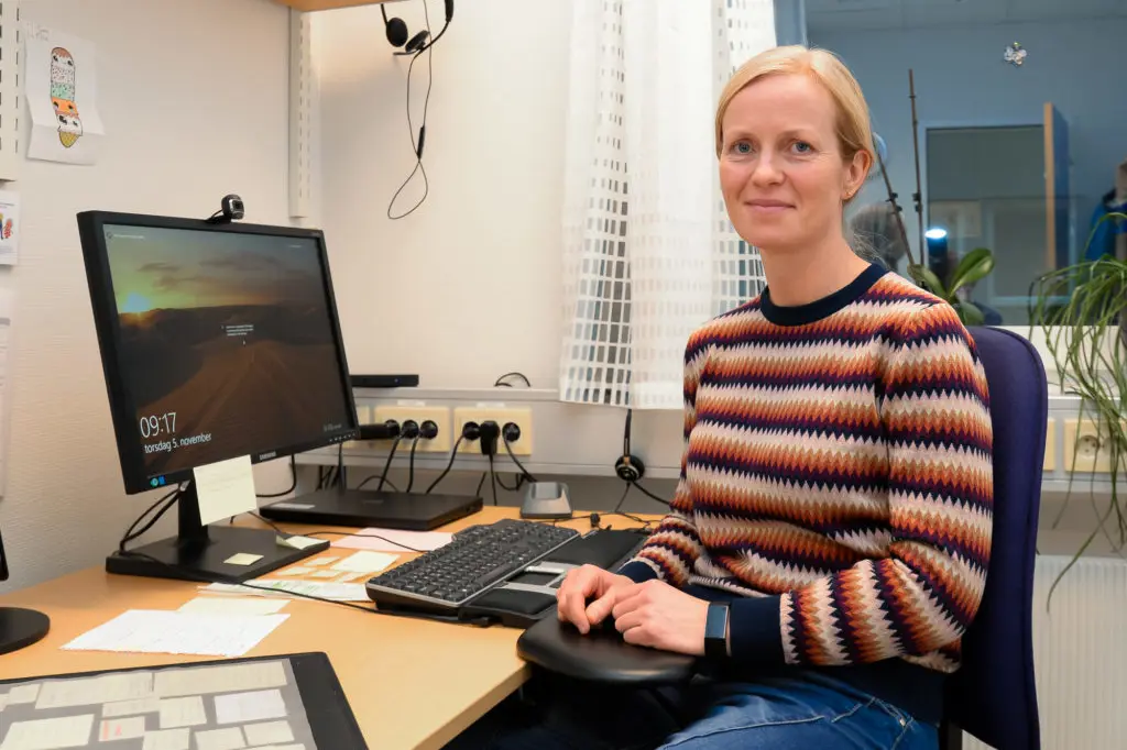 En person som sitter ved et skrivebord med en datamaskin