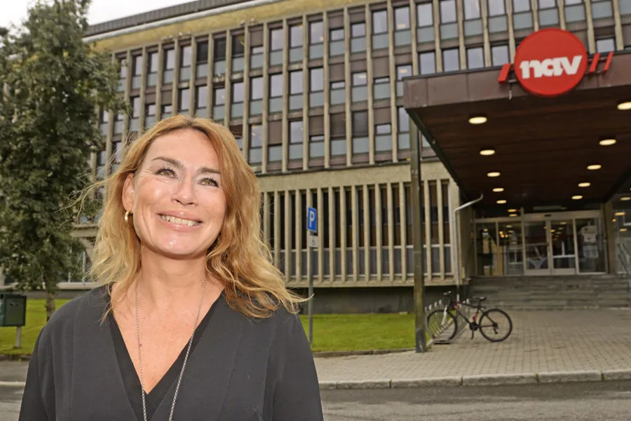 En person som smiler foran en bygning