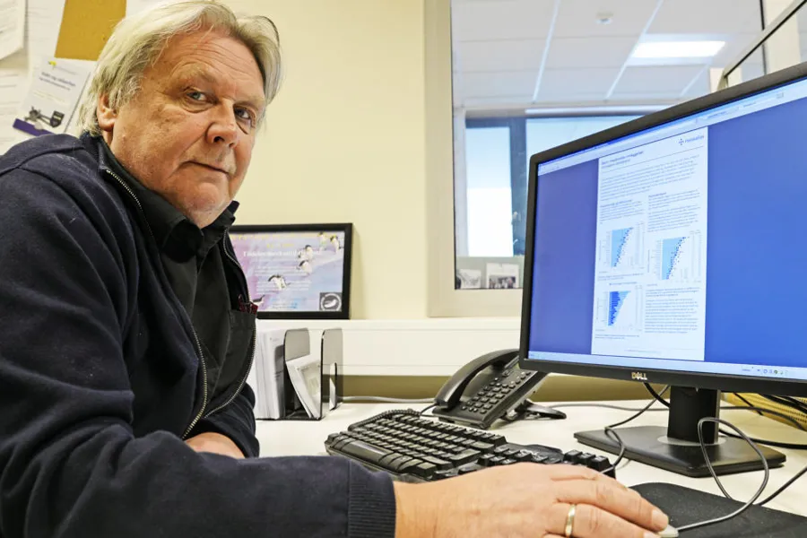 En mann som sitter ved et skrivebord med en datamaskin
