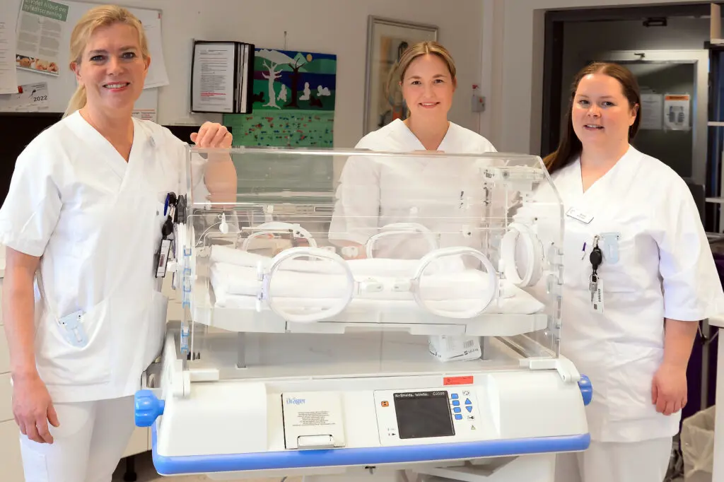 En gruppe kvinner i hvite laboratoriefrakker som står ved siden av en utstilling av medisinsk utstyr