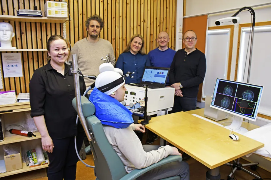 En gruppe mennesker som står rundt en person i en stol med en datamaskin