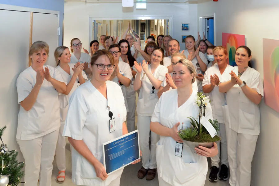 En gruppe mennesker iført hvite laboratoriefrakker som holder planter