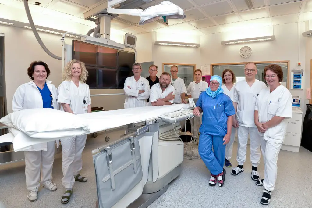 En gruppe mennesker i hvite laboratoriefrakker som står ved siden av en stor hvit maskin