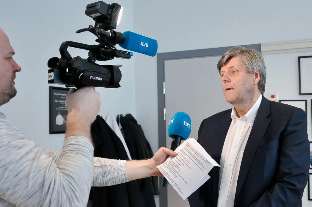 En mann som holder et papir og et kamera på et stativ