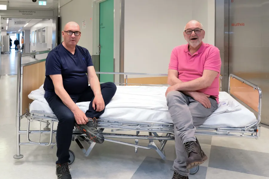 Et par menn som sitter på en sykehusseng