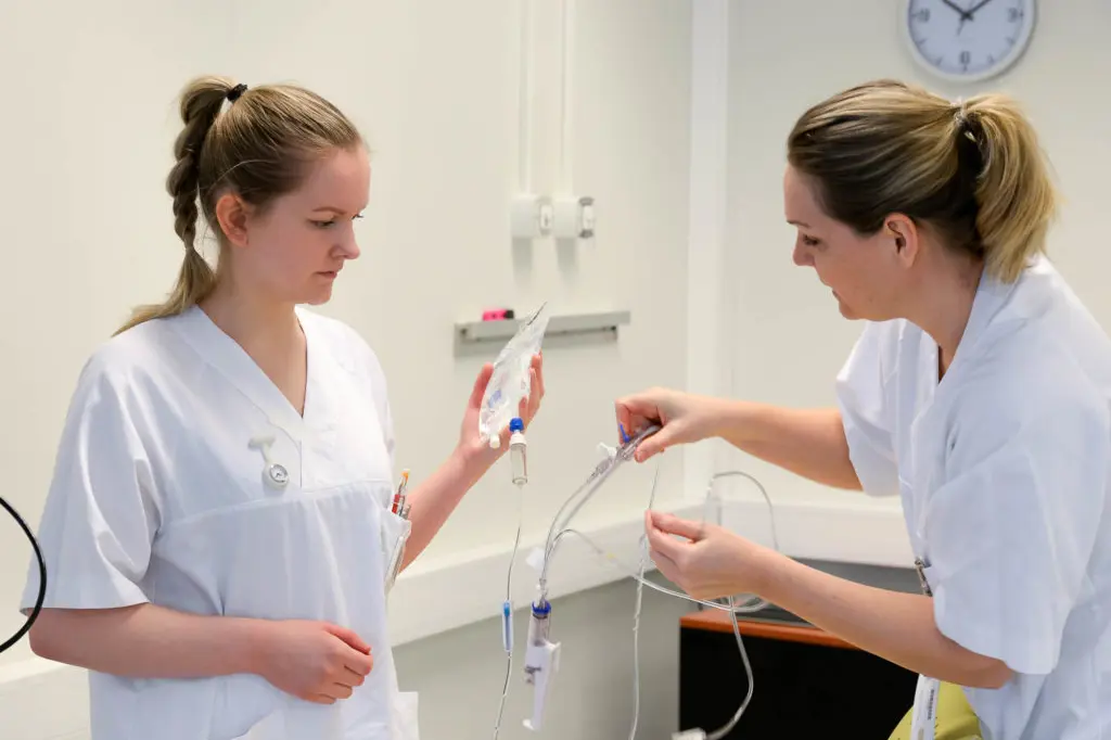 En lege som viser en pasient noe på datamaskinen