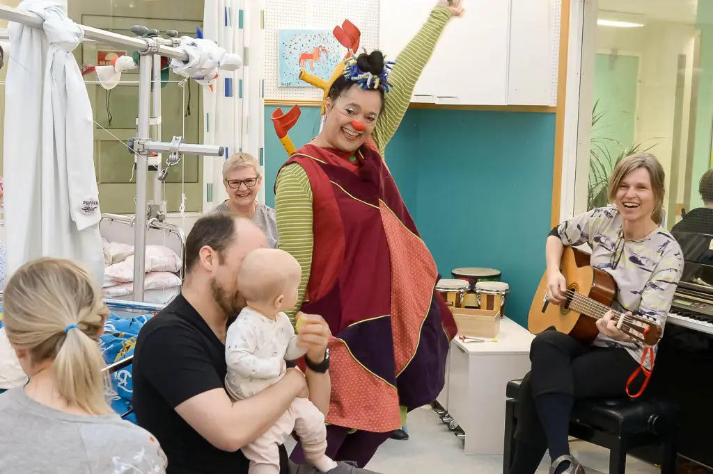 En mann i et klesplagg som holder en baby og en kvinne som holder en baby