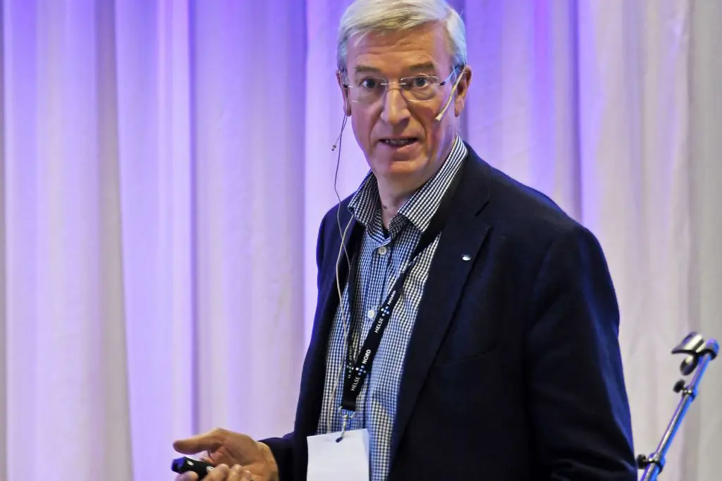 En mann i dress som snakker inn i en mikrofon