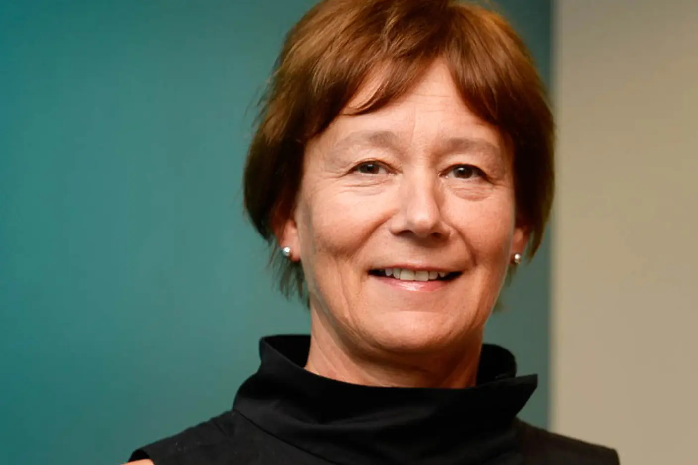 En person som smiler foran en blå vegg