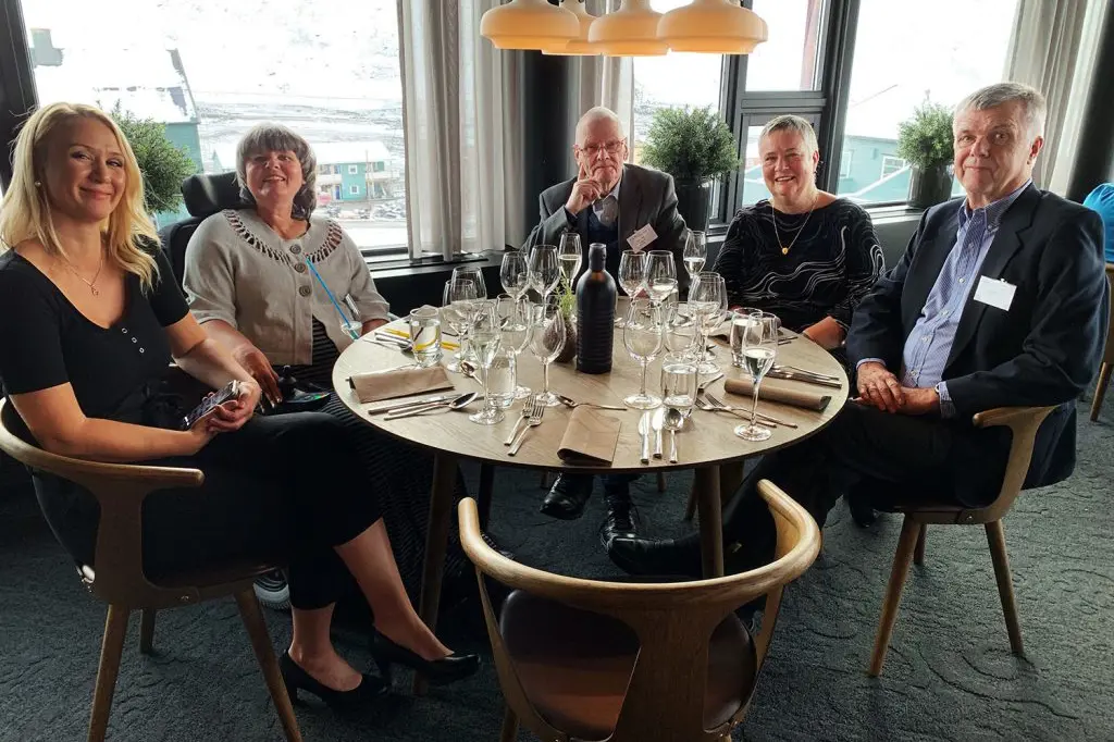 En gruppe mennesker som sitter rundt et bord med vinglass