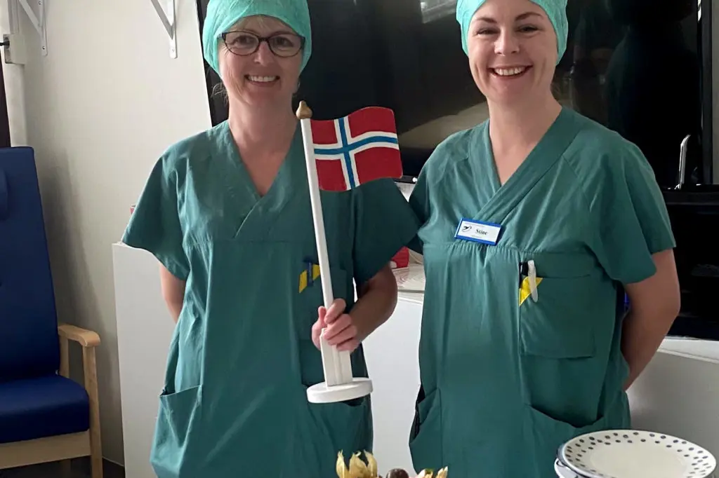 Kvinner i kirurgiske skrubb skjærer en kake
