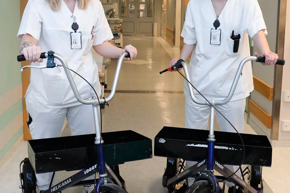Et par kvinner i hvite skjorter som står ved siden av en sykkel