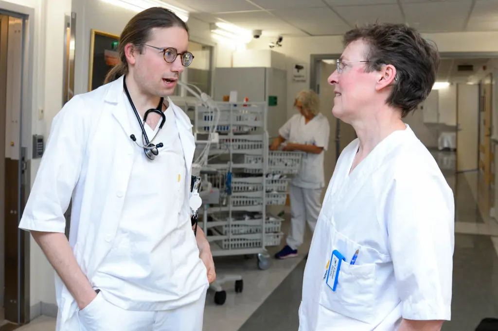 Et par menn i hvite laboratoriefrakker i et rom med hyller