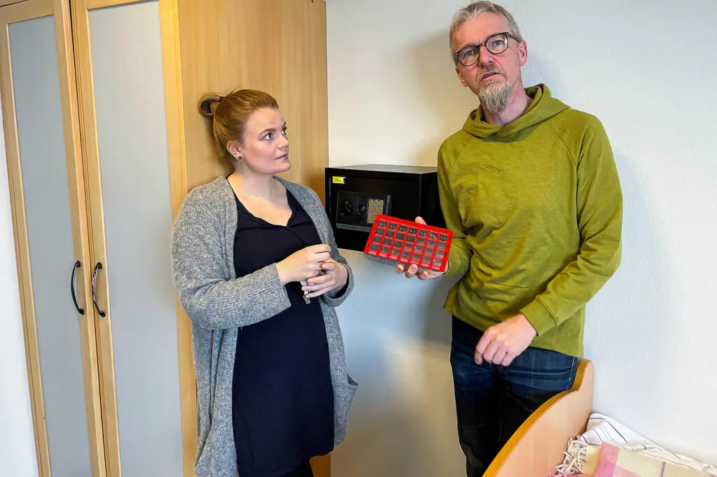 To personer på pasientrom viser fram hotellsafe til medisiner