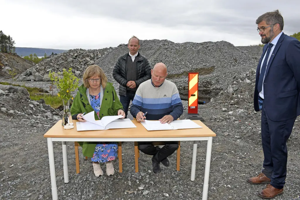 En gruppe mennesker som står rundt et bord med papirer på