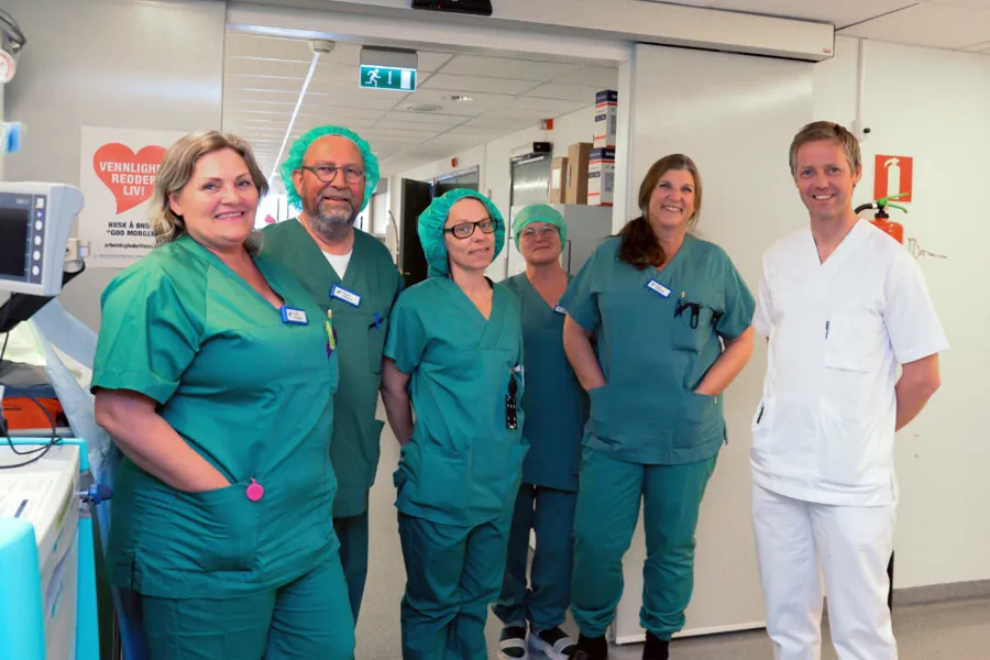 En gruppe mennesker i kirurgiske skrubb som poserer for et bilde