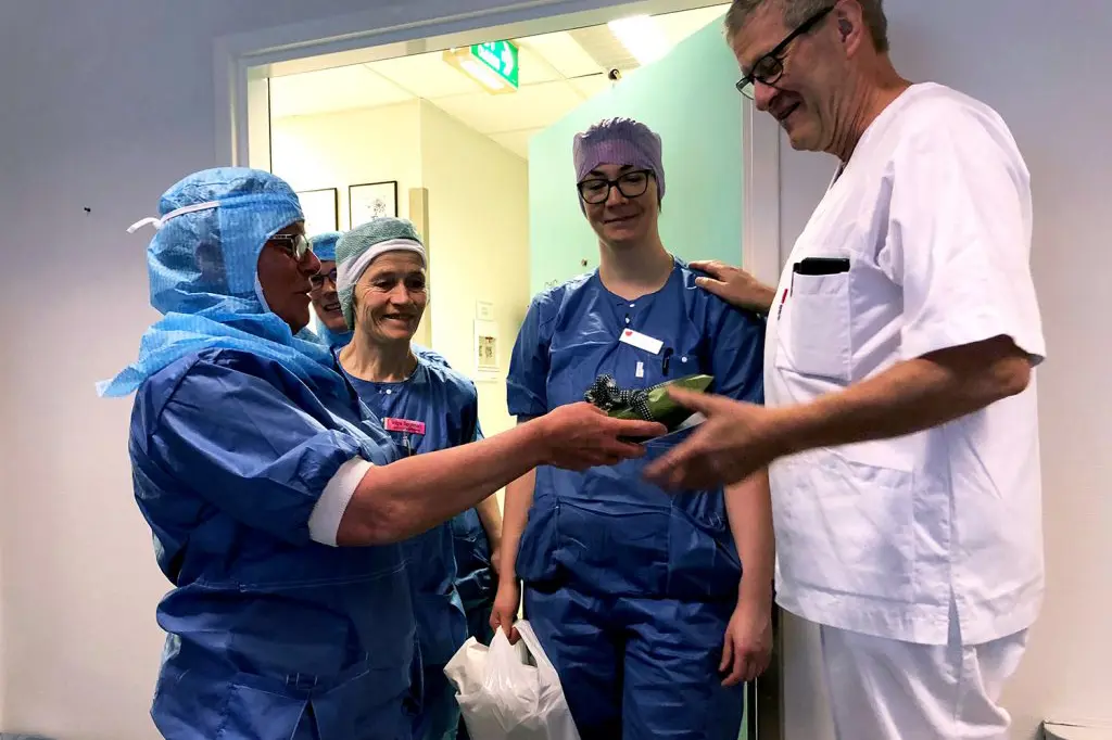 En gruppe mennesker i kirurgiske skrubb som ser på en enhet