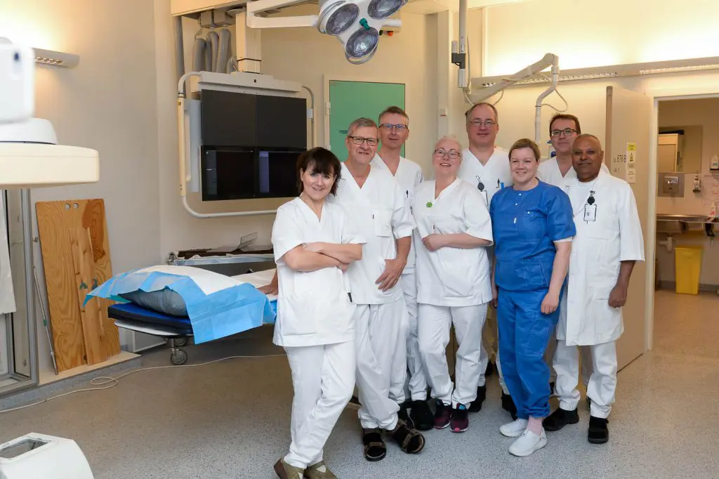 En gruppe mennesker i hvite laboratoriefrakker som står i et rom