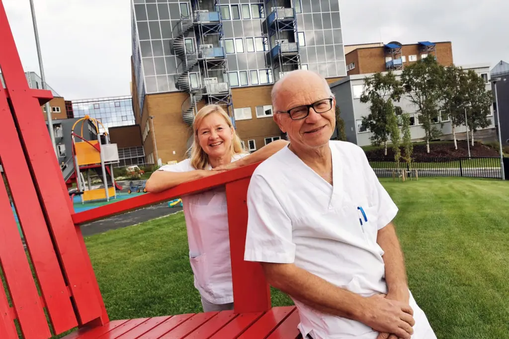 En mann og kvinne som sitter på en rød benk foran en bygning