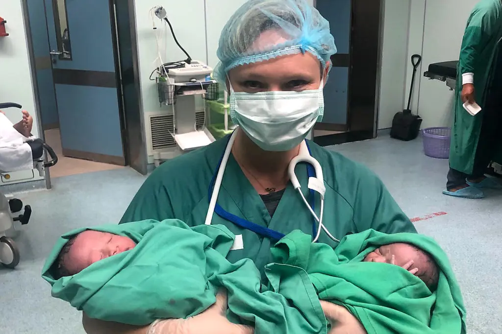 En person i kirurgisk skrubb som holder en baby