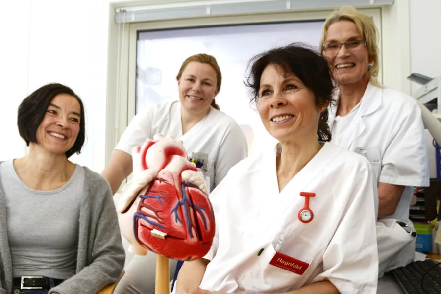 En gruppe kvinner i hvite laboratoriefrakker som holder en baby