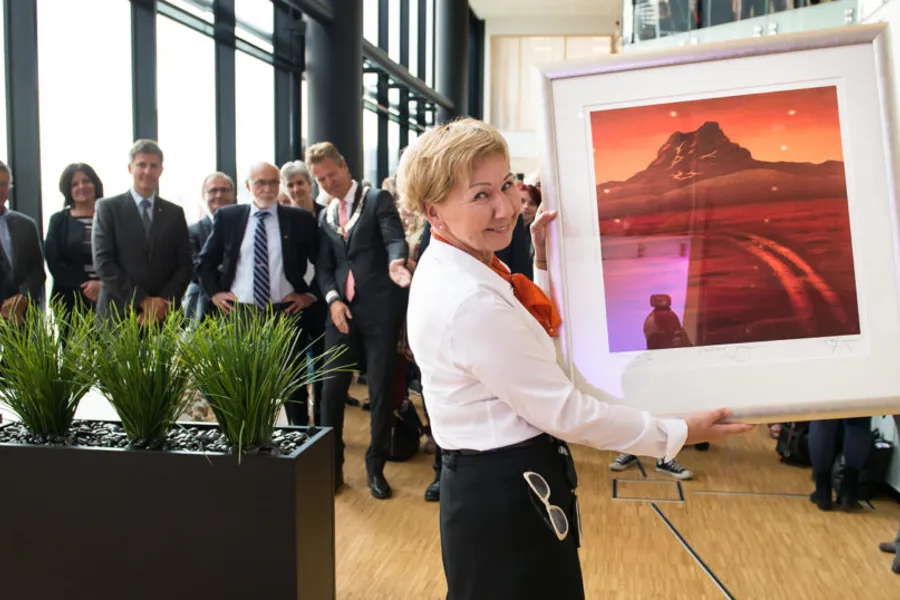 En person som står foran en skjerm med personer i bakgrunnen