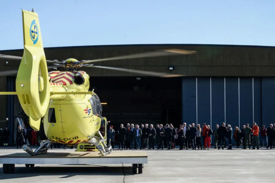 En gruppe mennesker som står ved siden av et helikopter