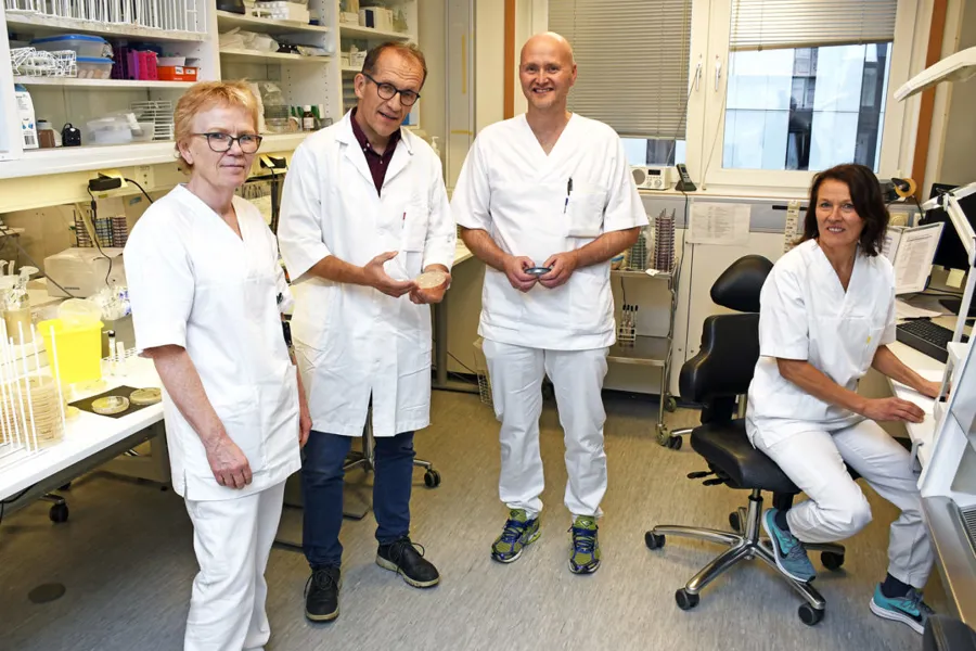 En gruppe mennesker i hvite laboratoriefrakker som står i et rom