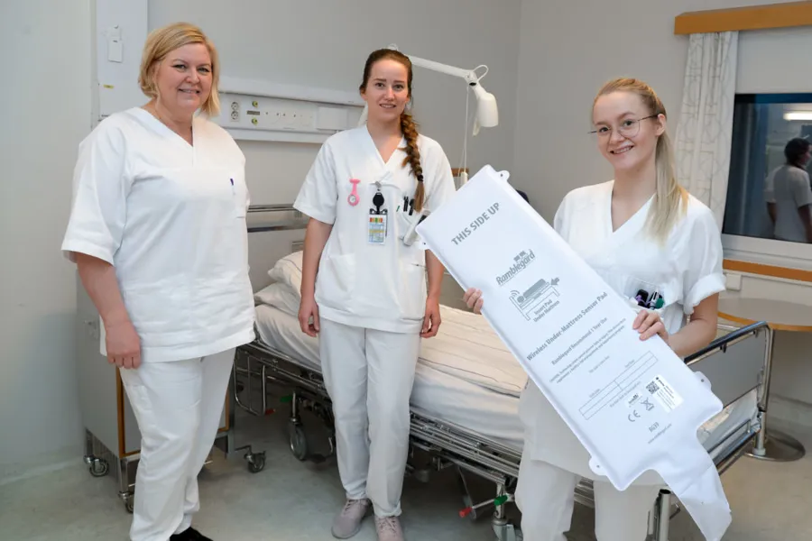 En gruppe kvinner i hvite laboratoriefrakker som holder et stort hvitt røntgenbilde