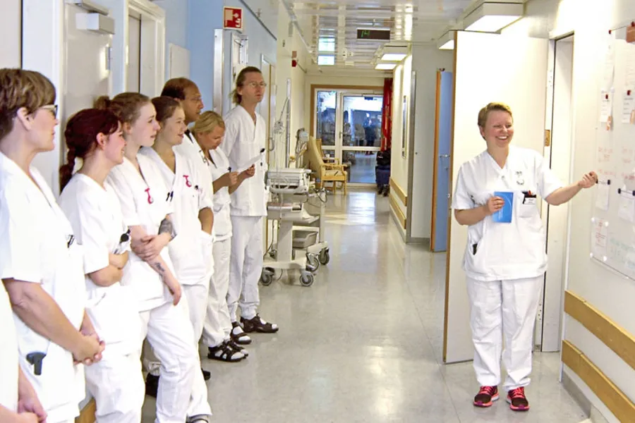 En gruppe mennesker i hvite laboratoriefrakker som ser på en tavle