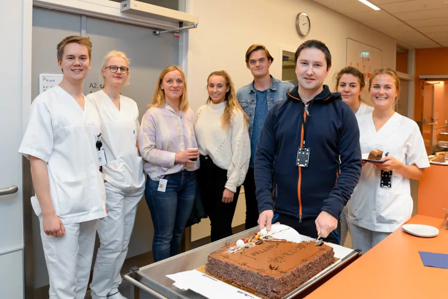 En gruppe mennesker som står rundt en kake