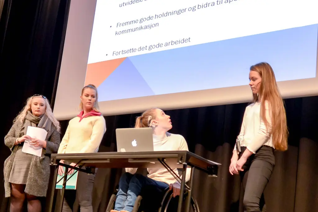 En gruppe mennesker som står rundt en kvinne i rullestol