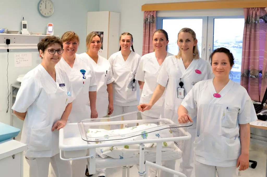 En gruppe kvinner i hvite laboratoriefrakker som står ved siden av et bord