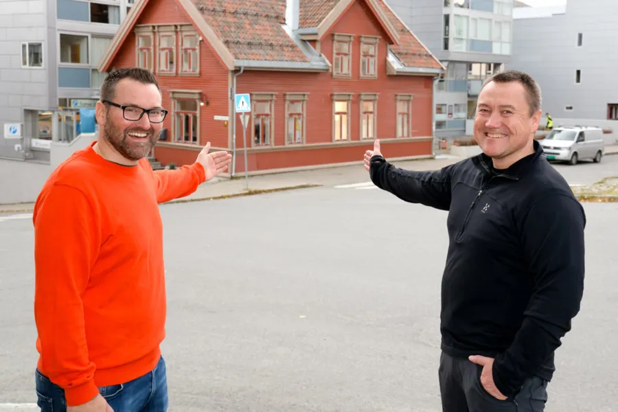 Et par menn som poserer for et bilde foran en bygning