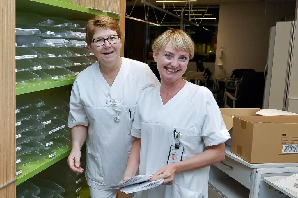Et par kvinner i hvite laboratoriefrakker som står i et rom med et vannbasseng